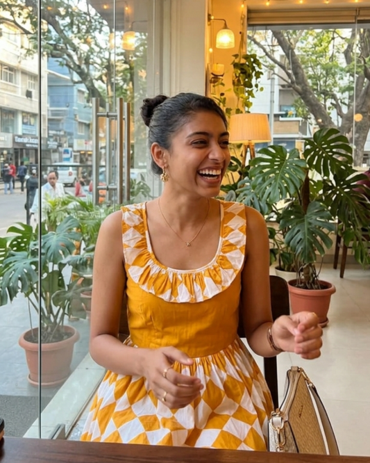 Woman in a yellow dress sitting inside a cafe with plants and city view outside